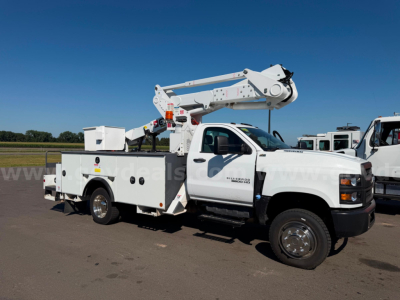 Utility bucket truck in-service showing cherry picker boom elevated on white Chevrolet Silverado 6500HD chassis with tool/storage compartments along side.
