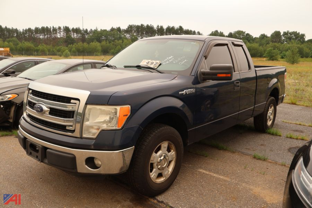 Ford F-150 extended cab pickup truck in blue with chrome front bumper and grille, 4-door, parked in lot.