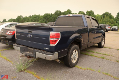 Ford F-150 extended cab pickup truck rear three-quarter view showing blue body, crew cab, and tailgate with Ford emblem.