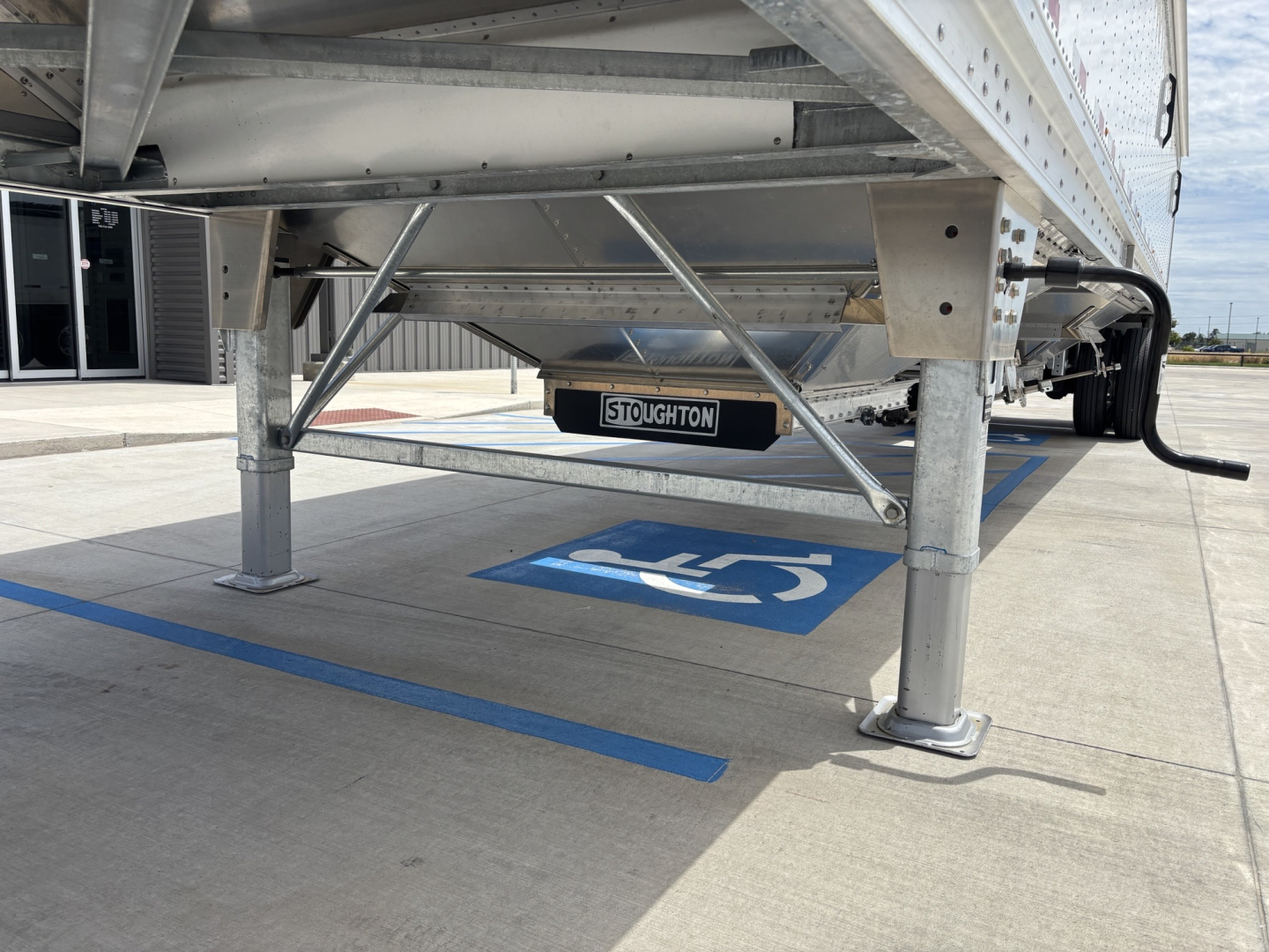 Aluminum grain hopper trailer underside showing support legs and Stoughton tag, 42' length with 68" side walls.