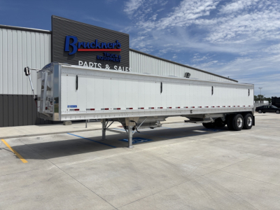 Stoughton 42' aluminum grain hopper trailer with 68" high sides, side view showing elevated front jack and dual axle rear, in front of dealership.