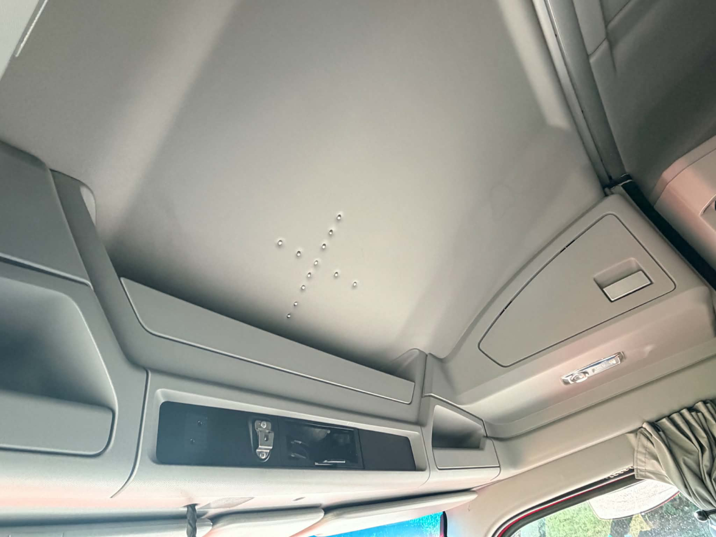 Cab interior of a 2023 Kenworth T680 showing overhead panel and a small control area with text labels.
