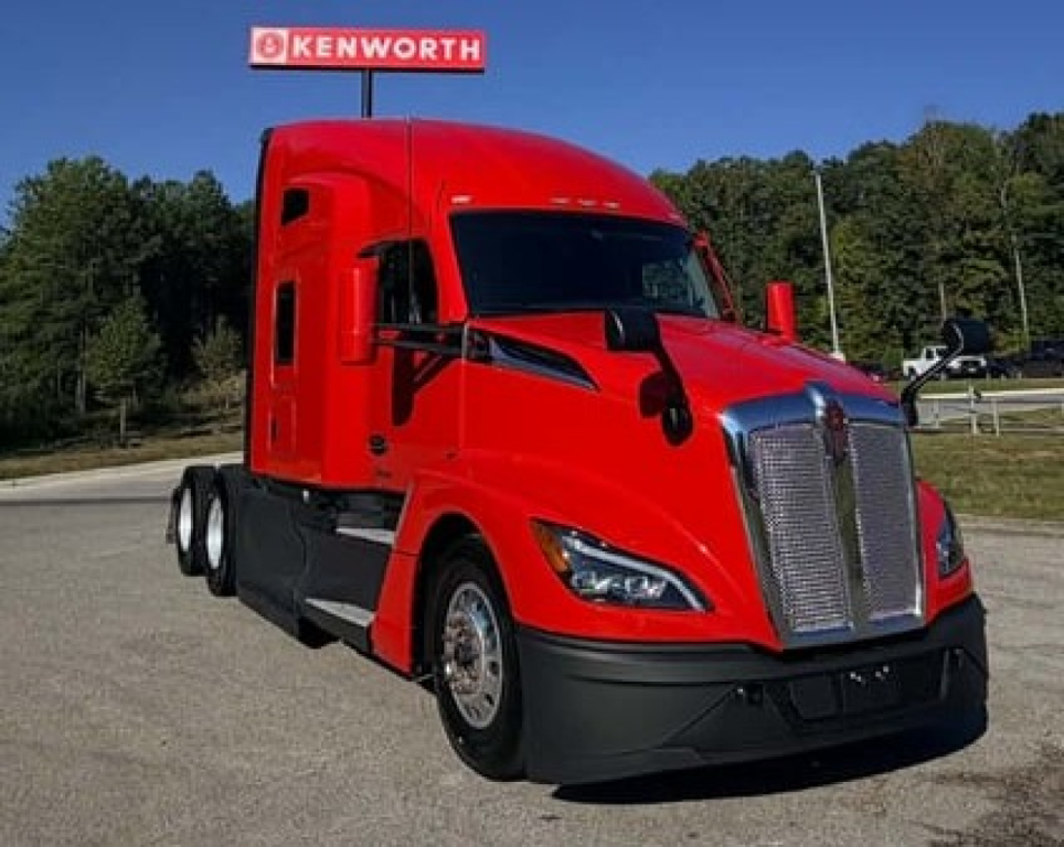 Kenworth T680 labeled red semi-truck in a dealership lot showing a bold chrome grille and aerodynamic cabin with black bumper.
