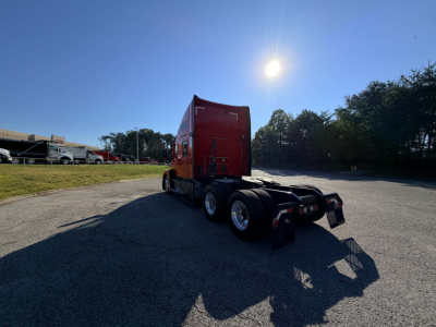 Kenworth T680 truck rear/side angle showing sleeper cab, red exterior, dual rear axles, unloaded chrome wheels, and trailer hitch. No legible text visible on components.