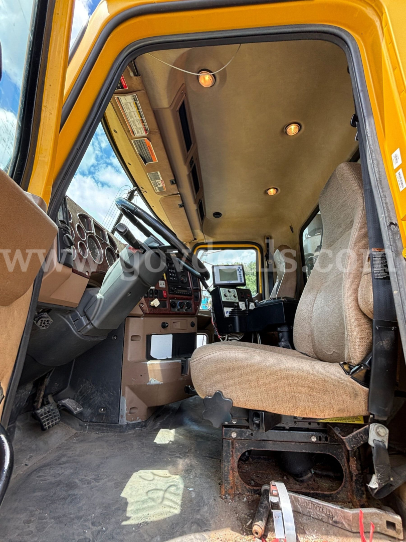 Cab interior of a 2008 Mack GU713 dump truck showing the driver seat, dashboard, and entry door.