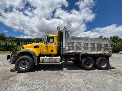 Dump truck side view showing 2008 Mack GU713 with yellow cab and gray dump bed.