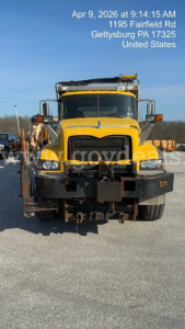 Front view of a yellow Mack GU713 dump truck with black bumper and plow; overlay text shows date/time and location: Apr 9, 2026 at 9:14:15 AM 1195 Fairfield Rd Gettysburg PA 17325 United States.