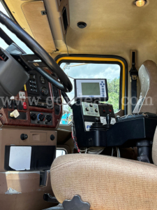 Interior of a Mack GU713 dump truck cab showing steering wheel, dashboard controls, and a mounted display unit.