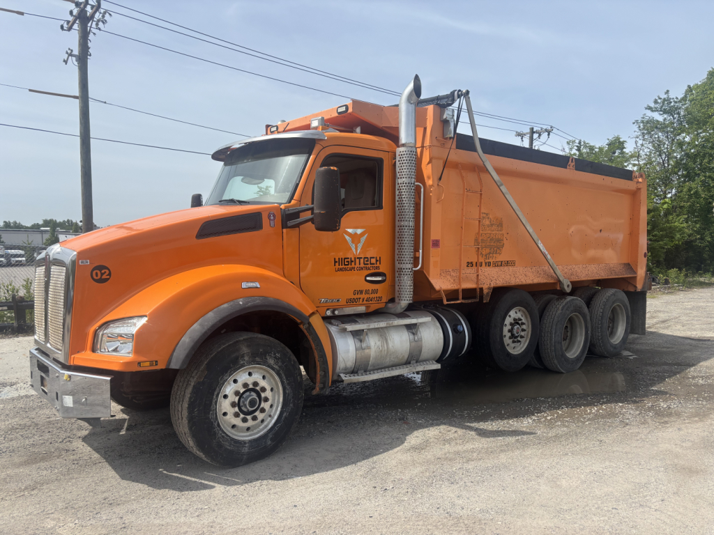 Orange Kenworth T880 dump truck with Six-wheel rear, cab side text shows Nighttech or similar branding, and truck VIN/number plate not legible.