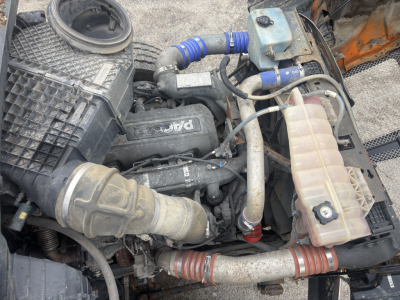 Kenworth T880 engine bay showing air intake, coolant reservoir, hoses, and engine components.