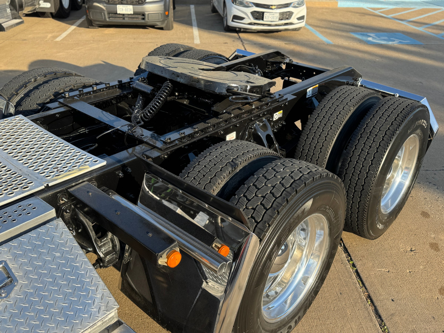 Kenworth truck chassis showing dual rear axles and fifth-wheel mounting with aluminum diamond plate toolbox and components visible.