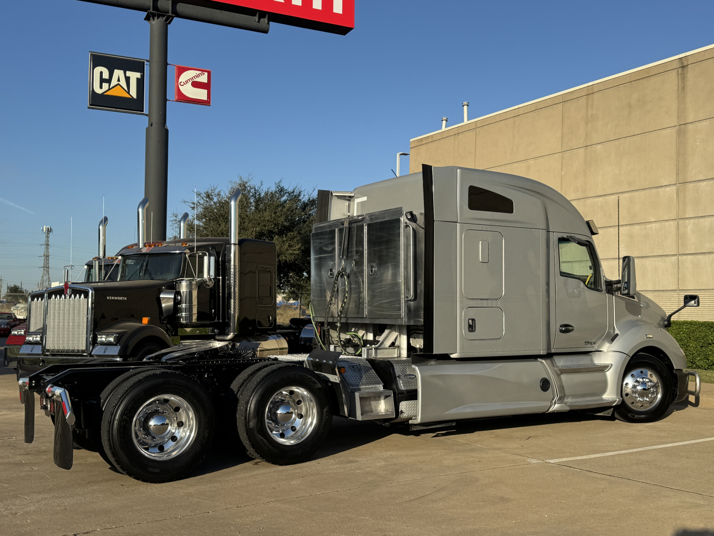 Kenworth T680 conventional sleeper truck in side view showing cab and chassis with chrome wheels and grey paint.