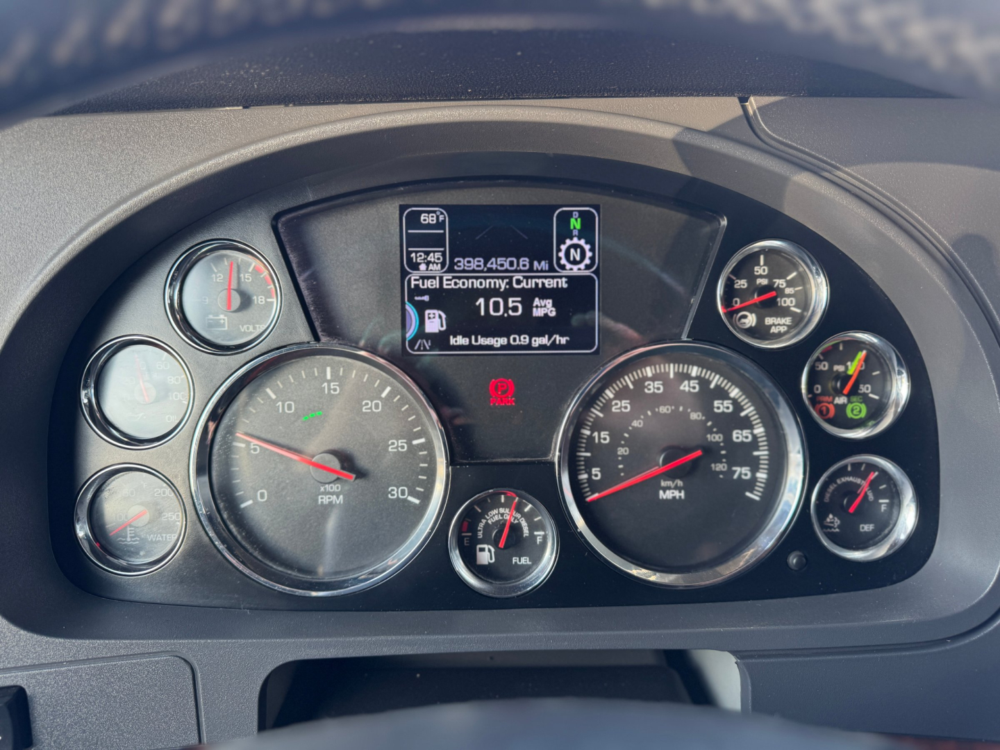 Kenworth T680 dashboard showing multiple round gauges, center digital display, and fuel economy readout.