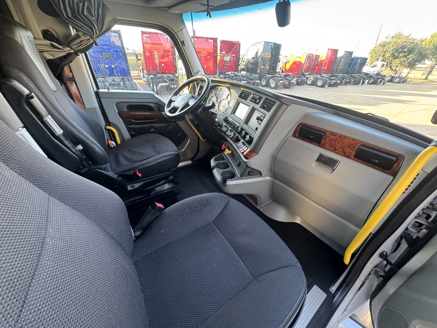 Interior cab of a 2021 Kenworth T680 truck showing steering wheel, dashboard, and seats. Visible text includes no explicit labels in the photo.