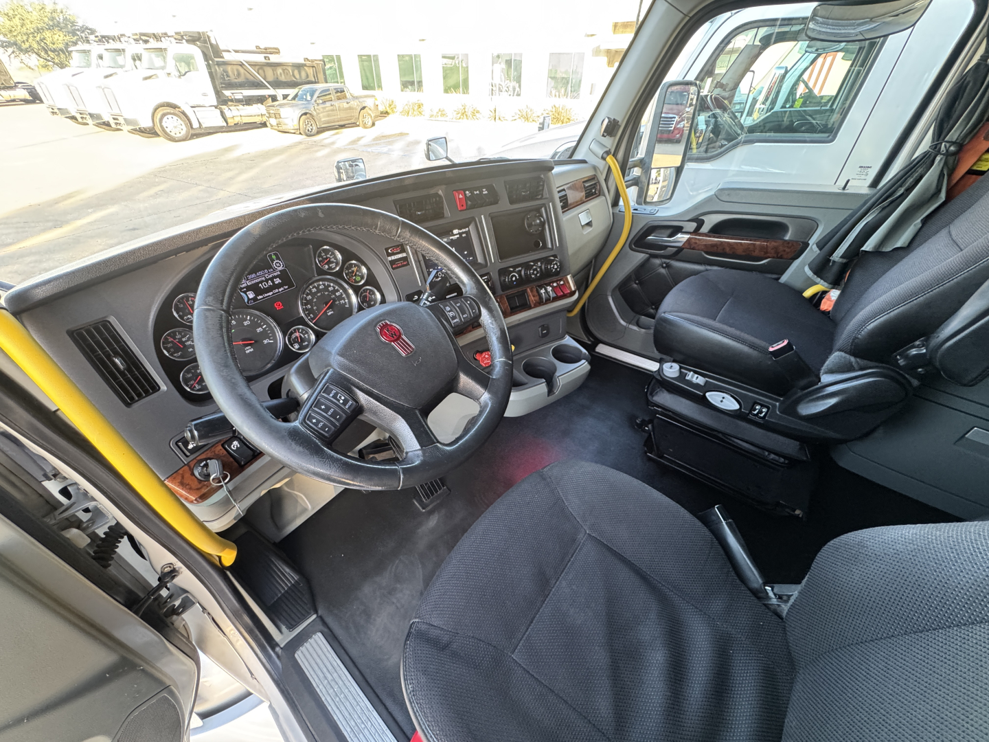 Interior of a 2021 Kenworth T680 truck cab showing steering wheel, dashboard gauges, and driver seat with center console.