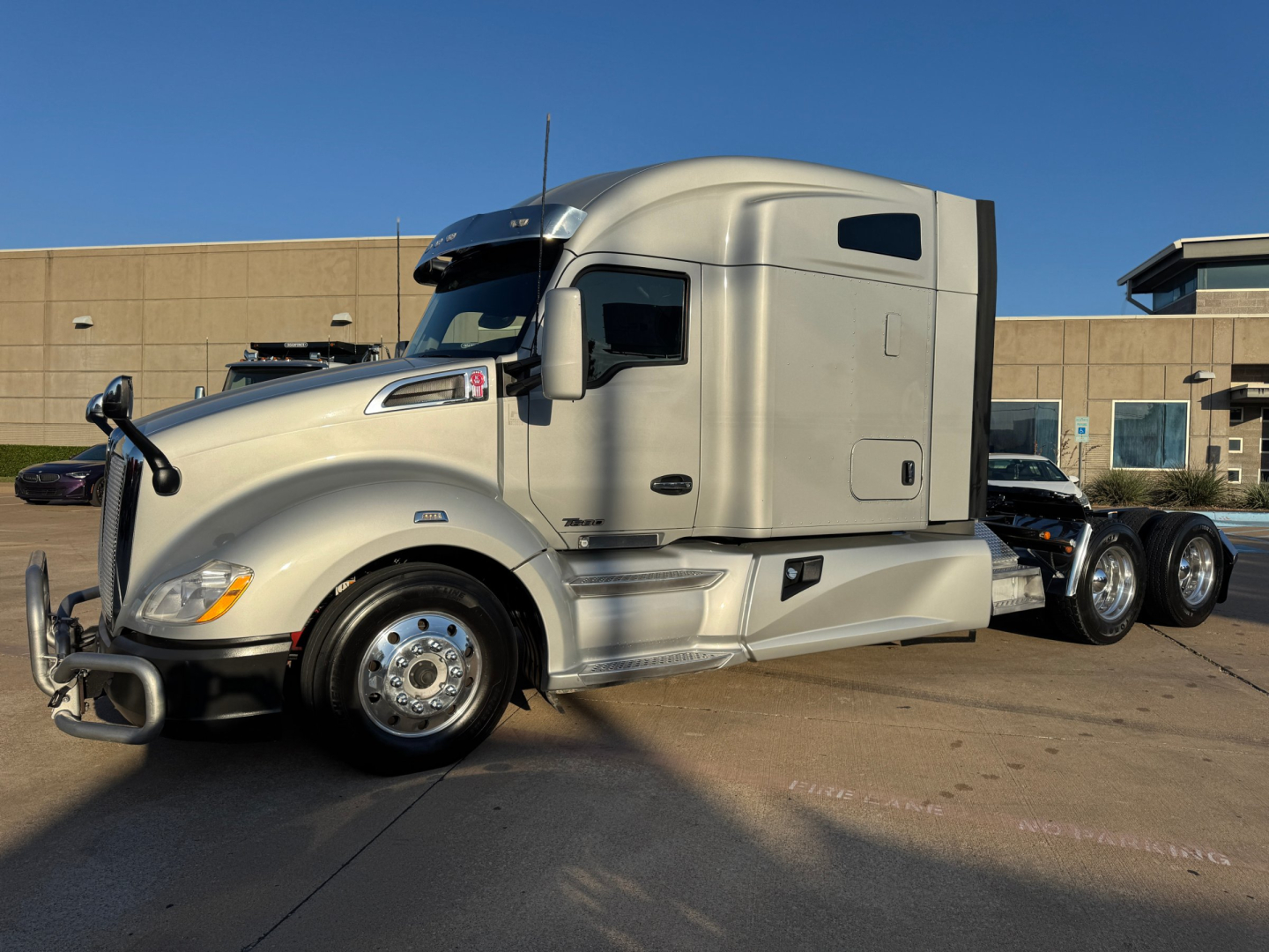 Kenworth T680 tractor in profile, shows front cab and sleeper, appears with beige exterior, chrome bumper, large fuel tanks, and dual rear axles.