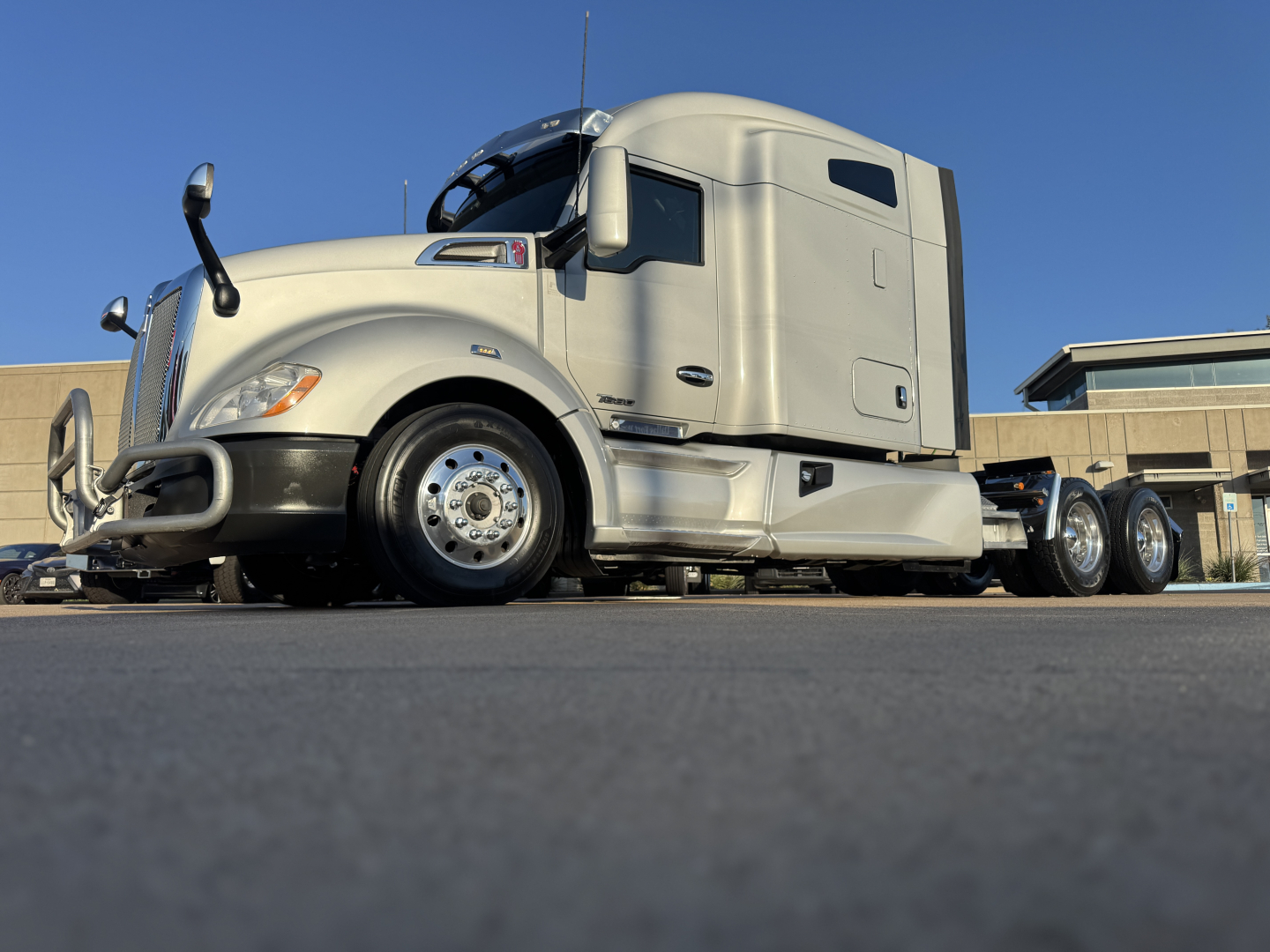 Kenworth T680 tractor-trailer in beige showing front grille and side cab details with wheels and sleeper cab
