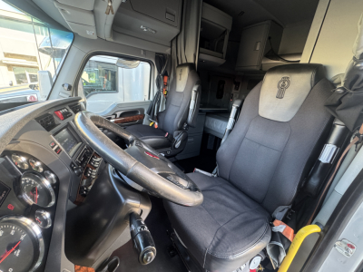 Kenworth T680 truck interior showing driver seat and dashboard with steering wheel and control stalks.