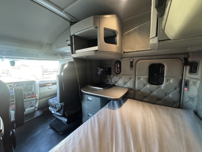 Kenworth T680 sleeper cab interior with overhead storage and bed, showing cabin area and side window.