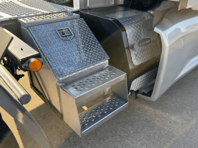 Kenworth T680 side step and fuel tank area showing diamond plate aluminum steps and Carrier label on tank cover.