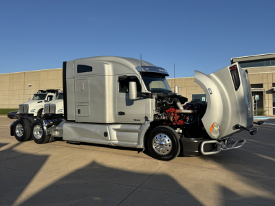 Kenworth T680 tractor with hood open, showing engine and side view. Front fender, chrome wheels, and gray body. No visible text labels.