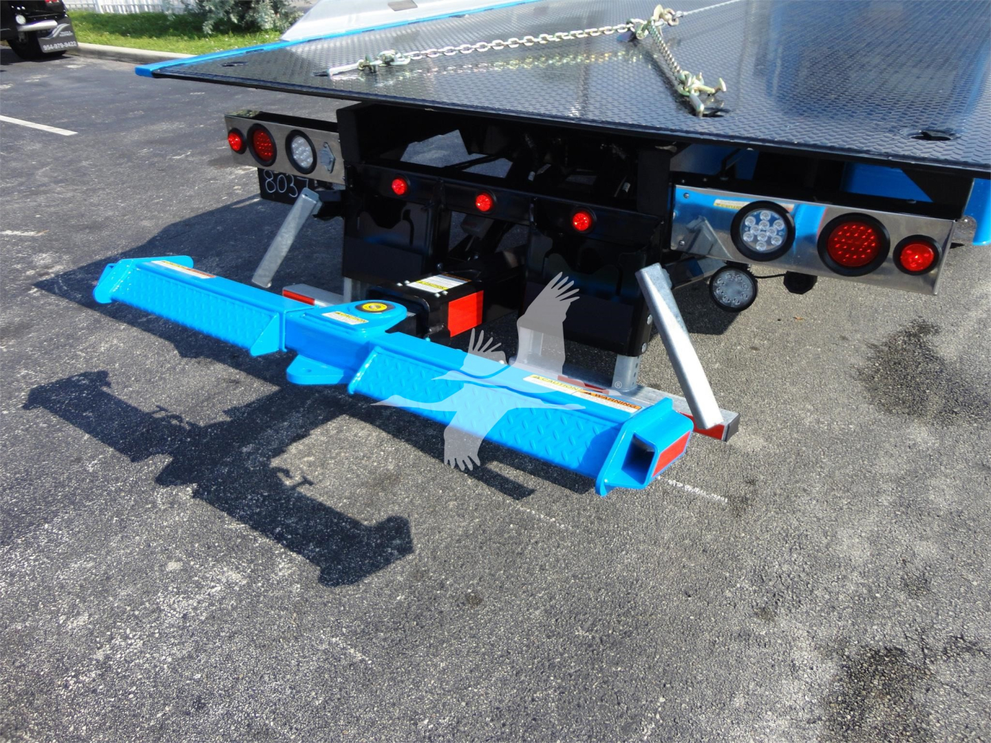 Blue underride protection bar attached to rear of 2022 Peterbilt 337 rollback truck with platform and safety lights.