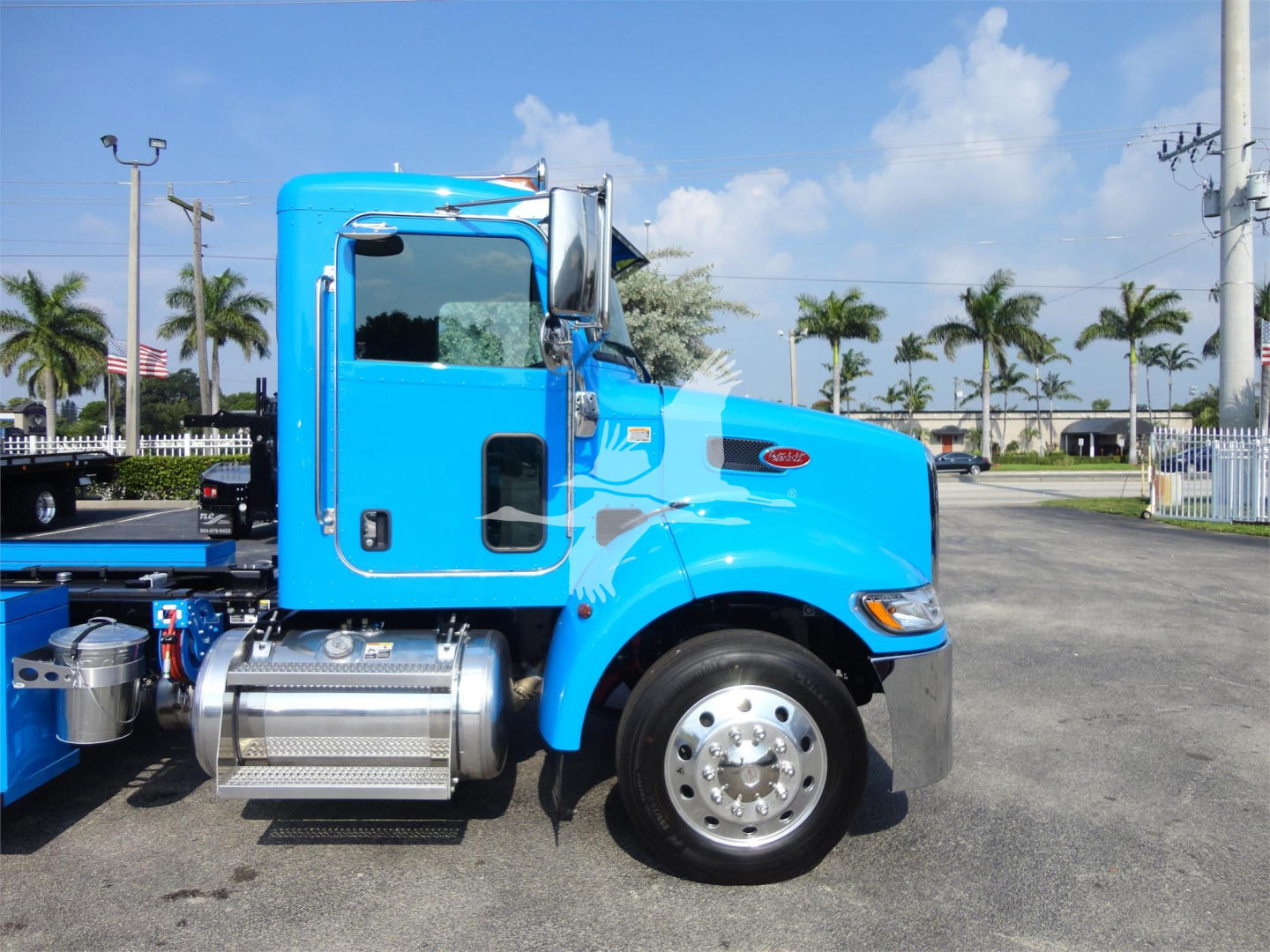 Blue 2022 Peterbilt 337 rollback truck side view showing cab, fuel tank, and front wheel with chrome hubcap.