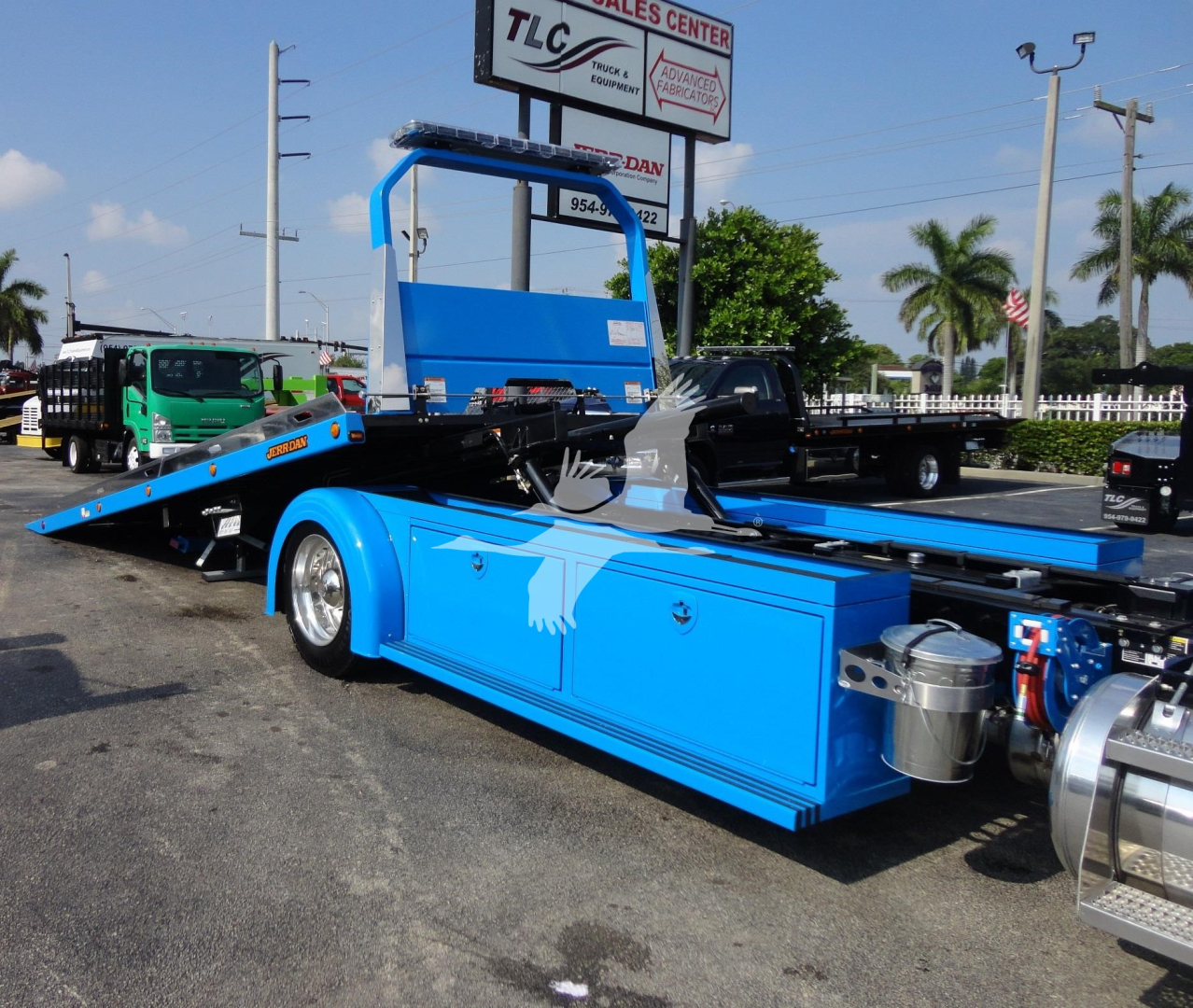 Blue Peterbilt 337 rollback tow truck side view showing mid-ship flatbed with hydraulic mechanism and chrome exhaust components.
