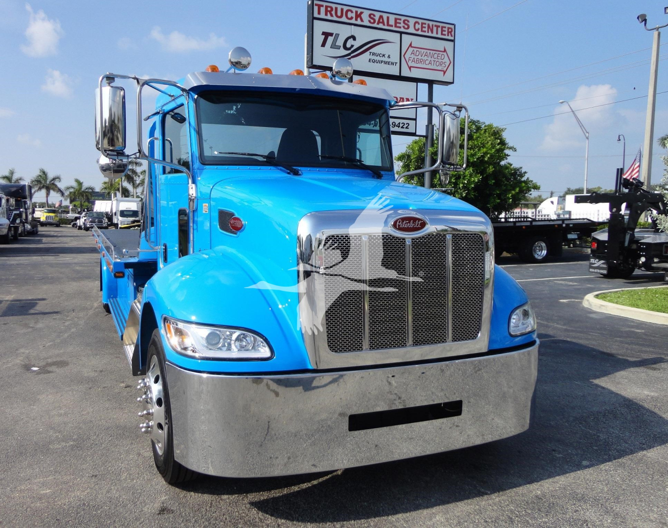 Blue 2022 Peterbilt 337 truck front view with large chrome grille and bumper, stock number J56606, in a dealership lot.