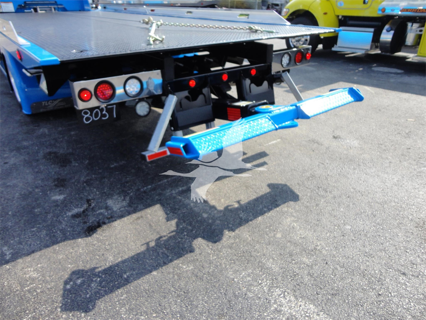 Peterbilt 337 rollback tow truck rear dresser with blue recovery ramps and hydraulic lift, showing rear bumper lights and tail area.