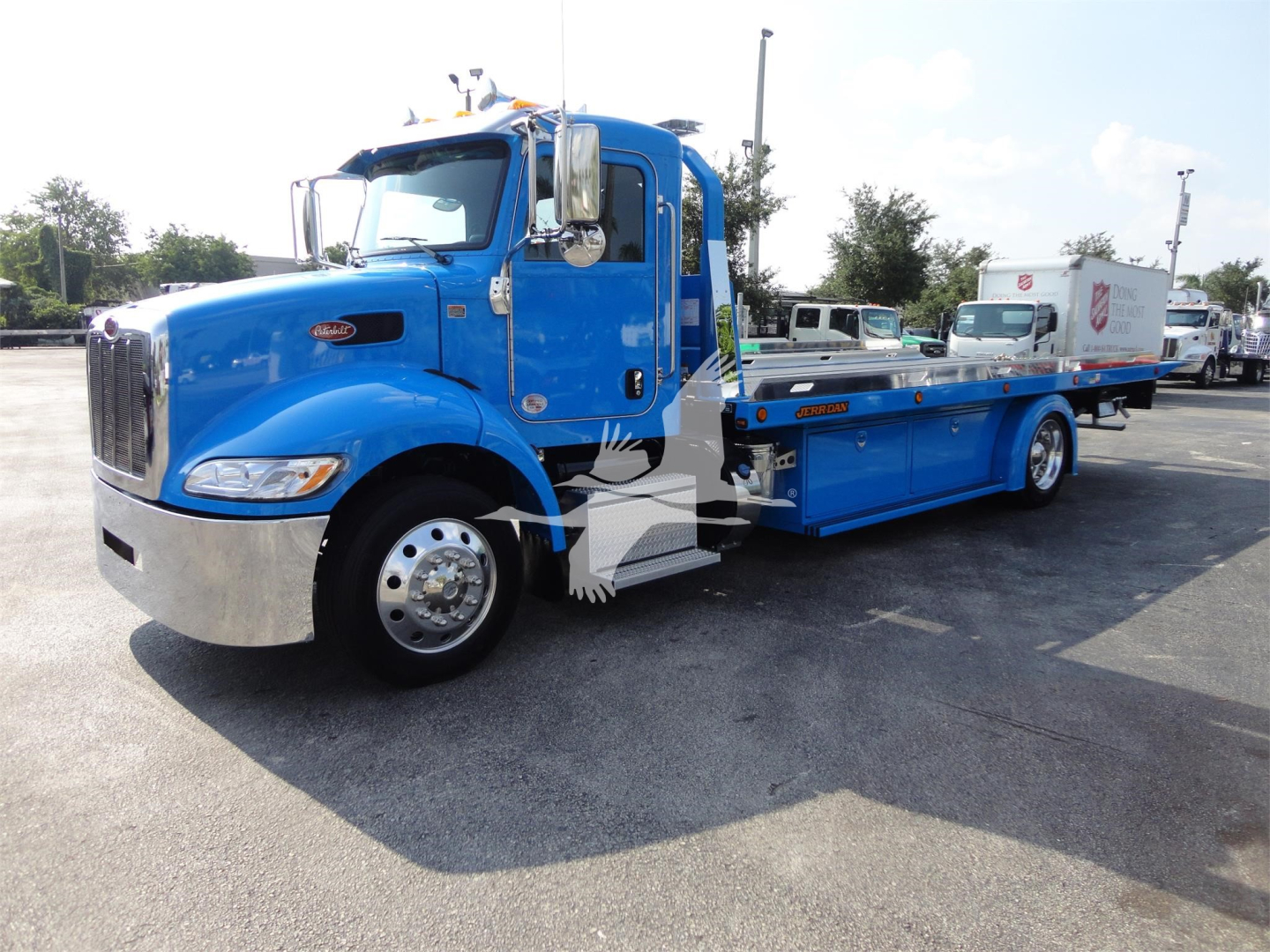 Peterbilt 337 rollback tow truck in blue, front-left view showing extended flatbed, chrome bumper, and dual mirrors.