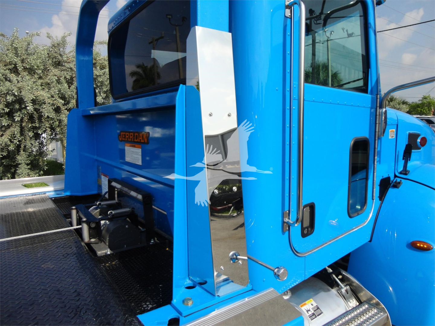 Blue Peterbilt 337 rollback truck cab side showing doors and rear platform with metal steps and safety rails.
