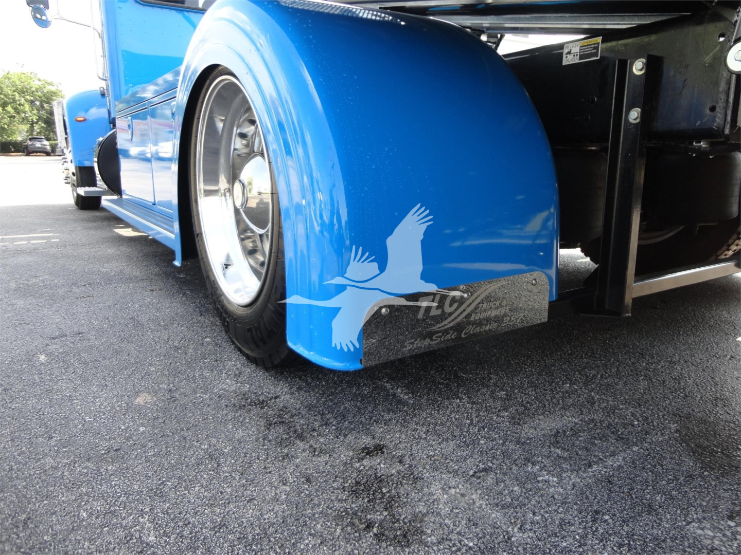 Peterbilt 337 rollback truck rear fender and wheel, blue paint, chrome wheel, mudflap with graphic, low-angle view.