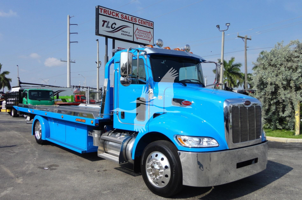 Peterbilt 337 rollback tow truck in blue, front-left view showing flatbed, chrome bumper, and side mirrors.