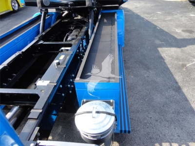 Truck chassis and blue service area of a 2022 Peterbilt 337 rollback truck showing hydraulic components and access platforms.