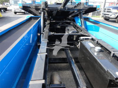 Truck bed undercarriage showing frame rails and hydraulic components of a blue Peterbilt 337 rollback truck