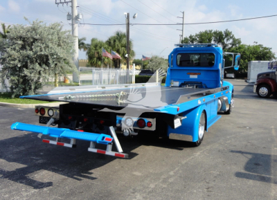 Blue Peterbilt 337 rollback tow truck rear view showing loading flatbed and rear lights.