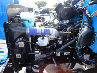 Peterbilt 337 engine bay showing coolant reservoir, air intake hose, and various hydraulic lines in blue and black components.