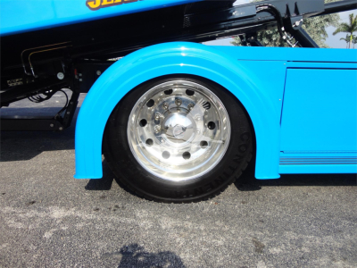 Rear wheel well and chrome wheel on a blue Peterbilt rollback truck; partial body with fender and lower side panel visible.