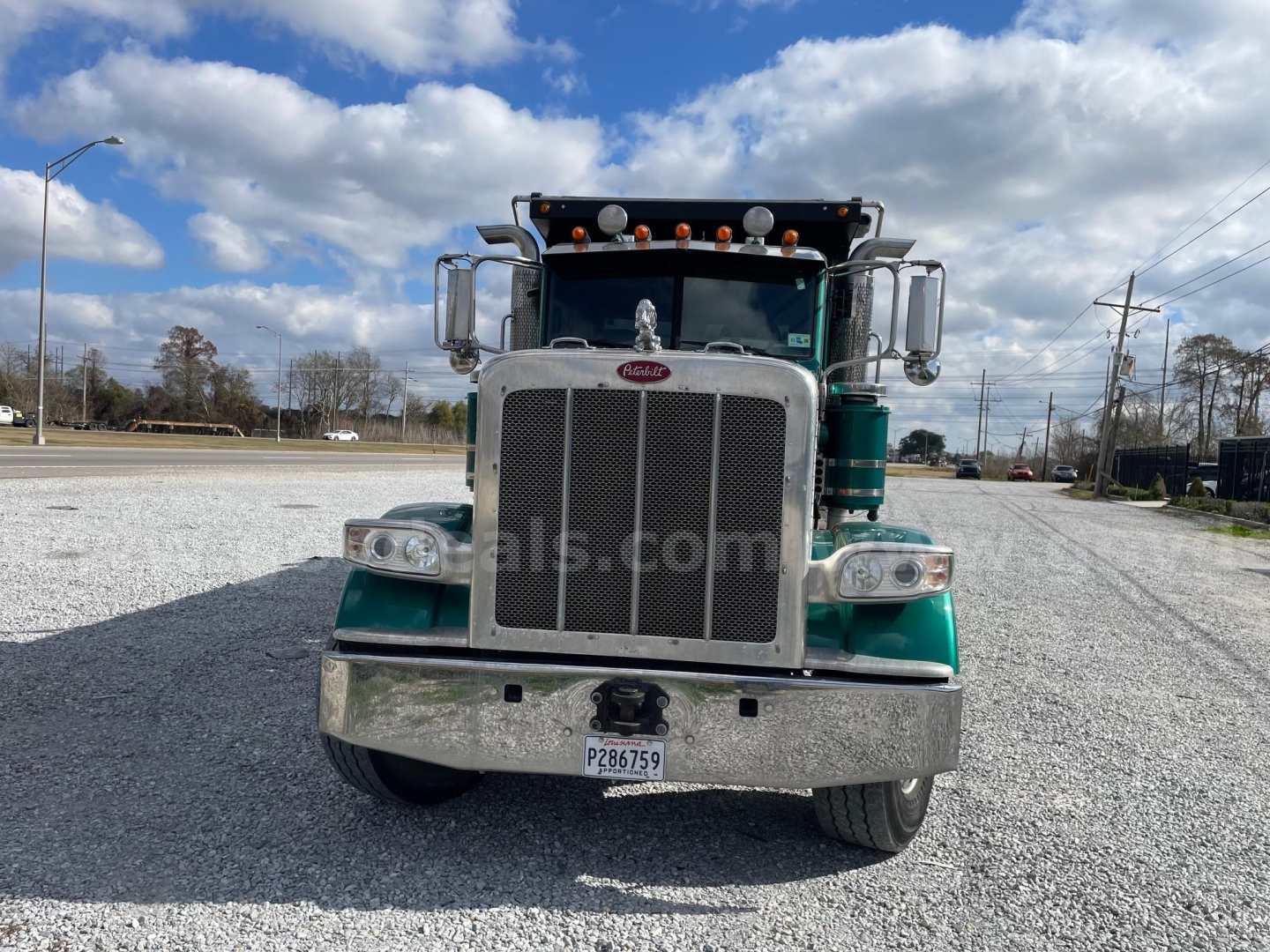 Peterbilt 388 dump truck facing front with chrome grille and bumper, white and green paint, dual mirrors, roof clearance lights on cab, and Mississippi-style license plate visible.