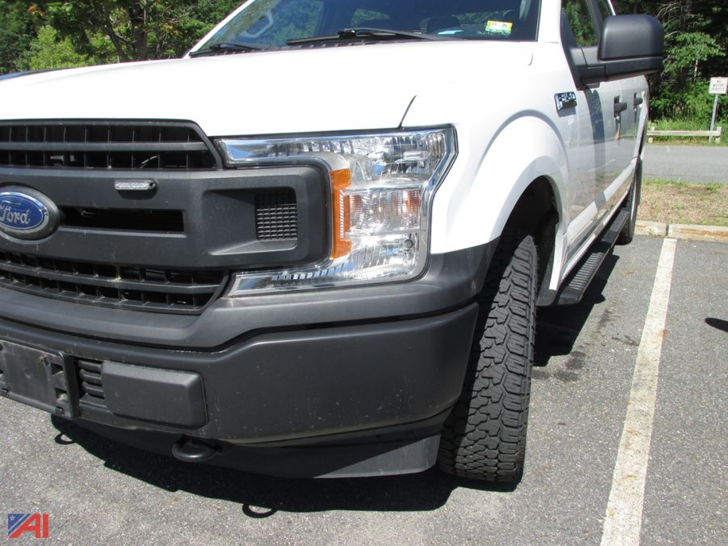 2020 Ford F-150 Crew Cab pickup front-left view showing grille, headlight, bumper, and front tire in a parking lot.
