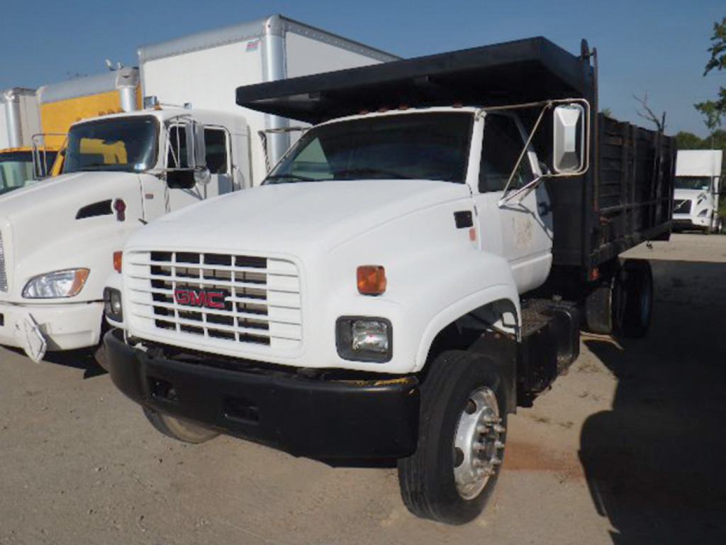 Front-left view of a white 2002 GMC C7 dump truck with a black dump bed, showing GMC grille, rectangular headlights, and side mirror.