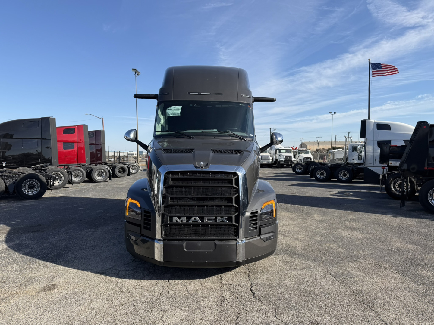 Front view of a new 2026 Mack PR64T76H sleeper tractor showing large black grille with Mack logo, headlights, and side mirrors.