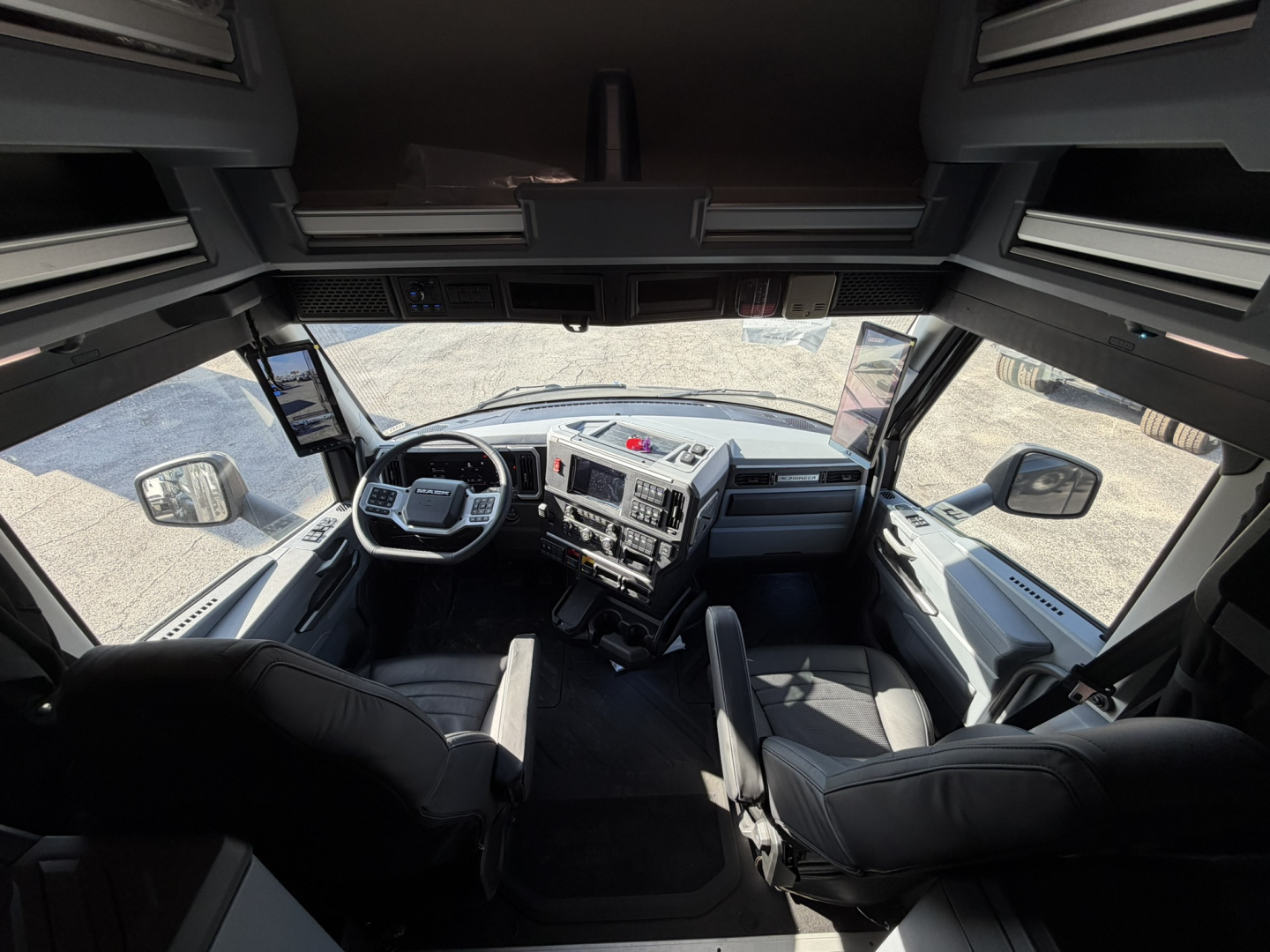 Truck cab interior of a 2026 Mack PR64T76H showing dashboard, steering wheel, and front seats from a wide-angle perspective.
