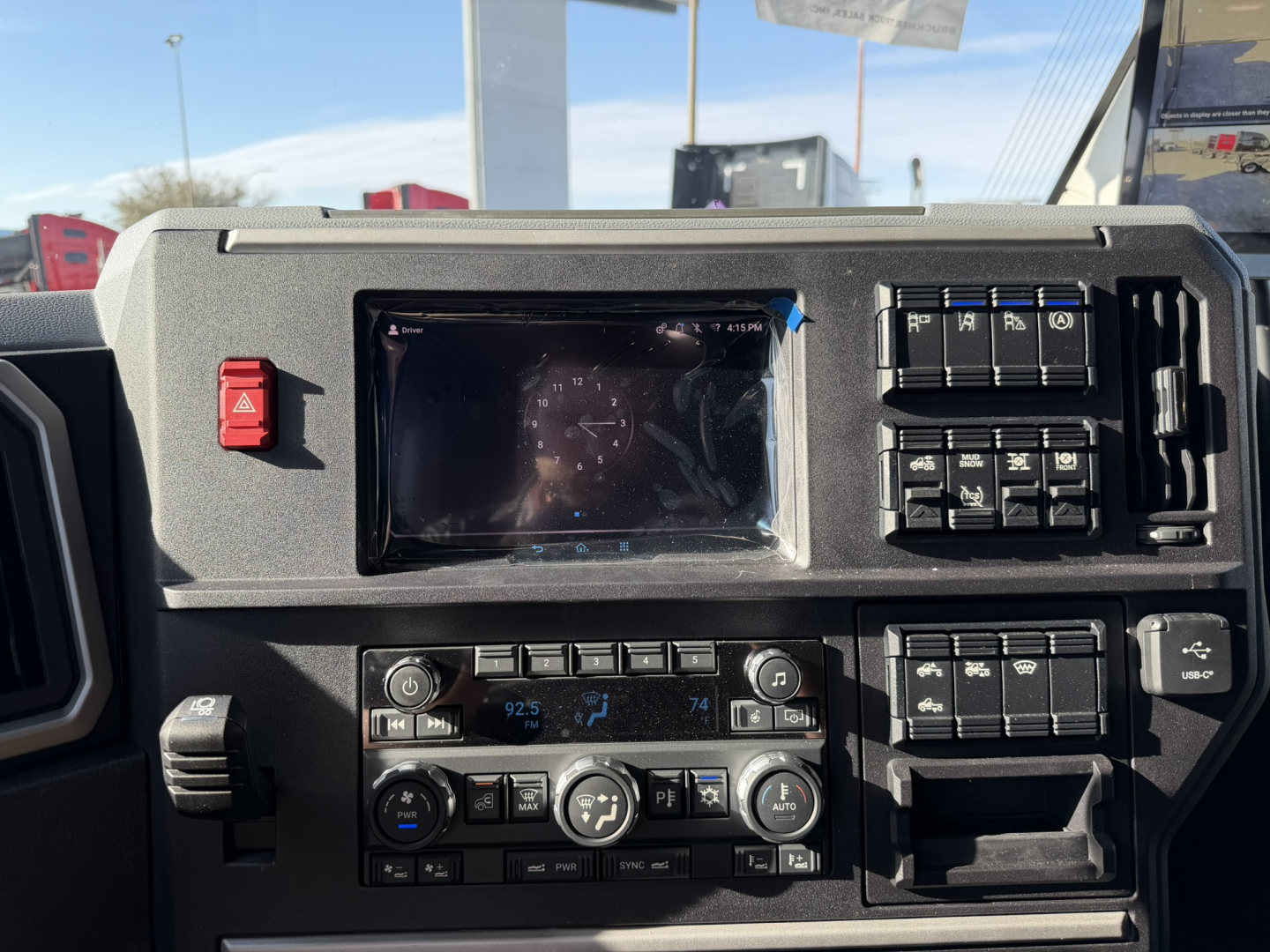 Dashboard view of a new Mack PR64T76H truck showing instrument cluster, climate controls, and switch panels.