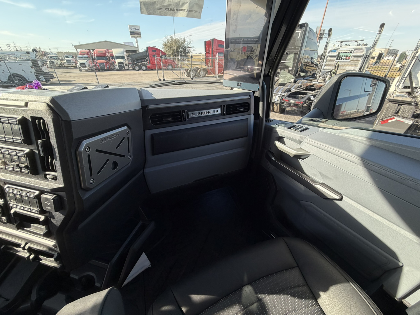 Dashboard and passenger side of Mack PR64T76H truck interior with open glove compartment and door panel.