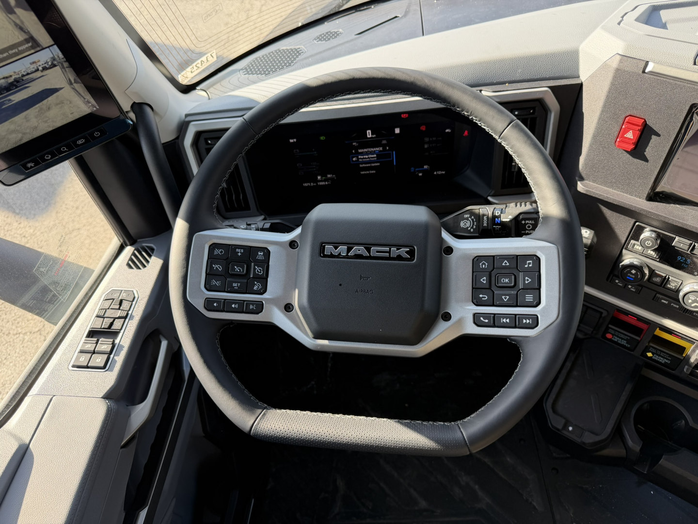 Steering wheel and dashboard of a new 2026 Mack PR64T76H truck cab interior showing Mack logo on steering wheel and control buttons.