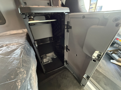 Cab interior showing a storage cabinet with shelves and a small drawer inside a Mack PR64T76H truck cab.