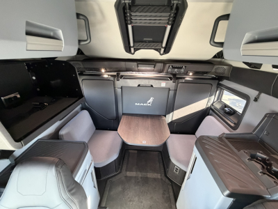 Cabin interior of a 2026 Mack PR64T76H showing bunk-style seating, table, and overhead storage with Mack logo on panels.