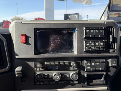 Dashboard view of a new Mack PR64T76H truck showing instrument cluster, climate controls, and switch panels.